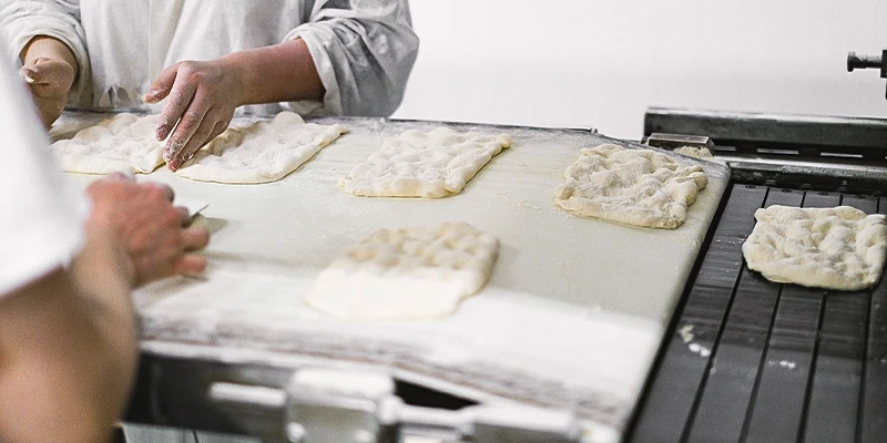 Travailleurs préparant des naans sur un tapis roulant dans une usine